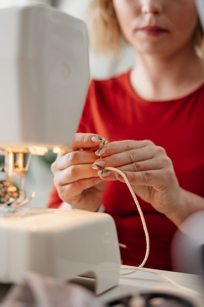 A focused woman threading a sewing machine, highlighting intricate craftsmanship.