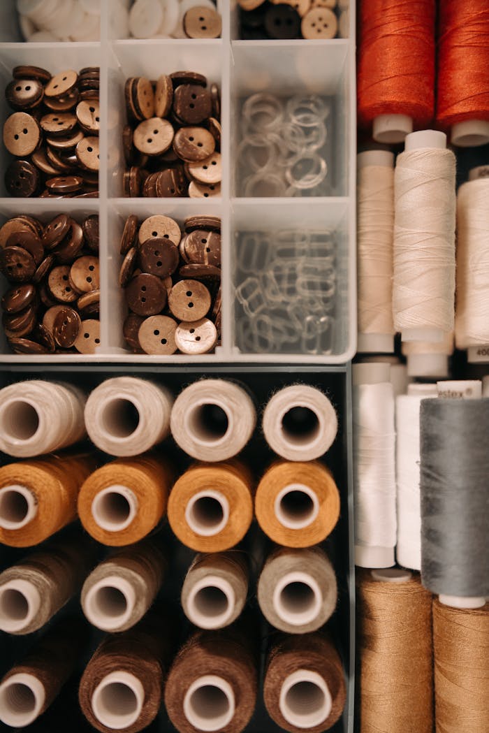 Top view of sewing materials including spools, threads, and buttons neatly arranged.